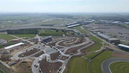 Aerial view of the Silverstone Circuit, a tapestry of asphalt and green fields, under a pale blue sky, Silverstone, Northamptonshire, United Kingdom.