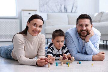 Parents and their son playing with toys on warm floor at home. Heating system