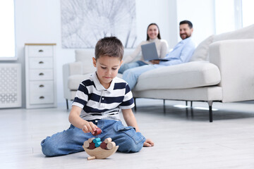 Boy playing with toys near his parents on warm floor at home, selective focus. Heating system