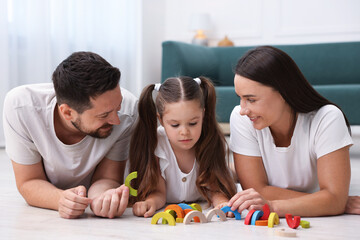 Parents and their daughter playing with toys on warm floor at home. Heating system