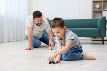 Father and his son playing with toys on warm floor at home, selective focus. Heating system