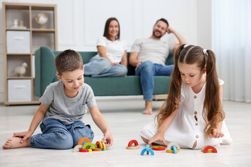 Kids playing with toys near their parents on warm floor at home, selective focus. Heating system