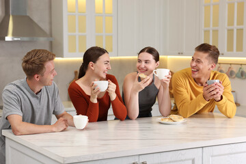 Friends with coffee laughing in kitchen. Positive emotion