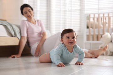Mother with her cute little baby on floor indoors, selective focus
