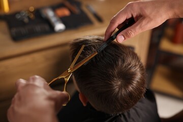 Professional barber cutting boy's hair in barbershop, above view