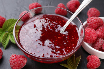 Sweet raspberry jam in glass bowl and berries on gray table, closeup