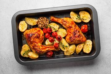Oven roasted chicken leg quarters with potatoes, tomatoes, garlic and herbs