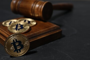 Cryptocurrency. Bitcoins and judge's gavel on black table, closeup. Space for text