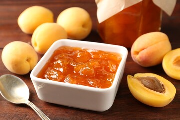Tasty apricot jam, fresh fruits and spoon on wooden table, closeup