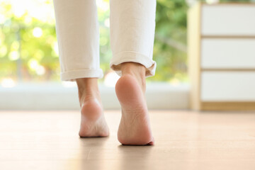 Woman walking barefoot on warm floor indoors, closeup. Underfloor heating