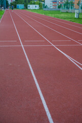 An empty red running track with white start and finish lines at an outdoor athletic stadium, a background with copyspace, concept of sports, competition, motivation.