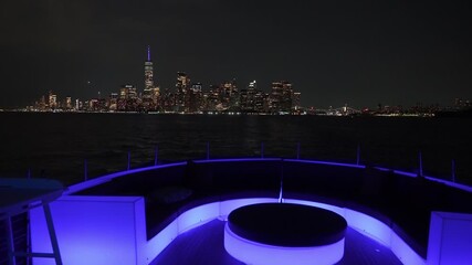 A stunning night scene showcasing the NYC skyline from a luxury yacht, illuminated by colorful lights
