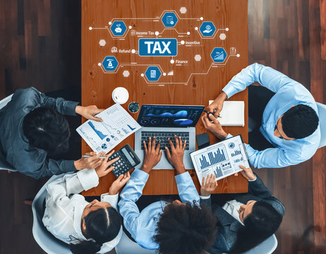A diverse team collaborates on tax strategies and financial analysis using laptops, documents, and charts, fostering a productive work environment. Amity