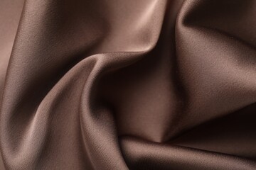 Crumpled light brown silk fabric as background, closeup