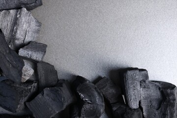 Pieces of black coals on grey table, top view. Space for text