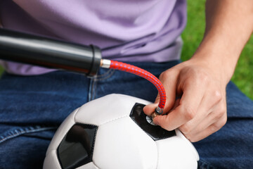 Man inflating soccer ball with manual air pump indoors, closeup