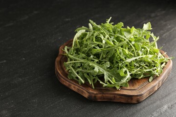 Fresh ripe green arugula leaves on black table, closeup. Space for text