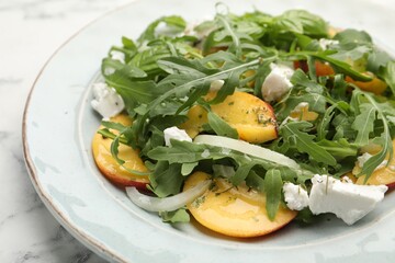 Tasty salad with arugula, cheese, peach and basil on white marble table, closeup