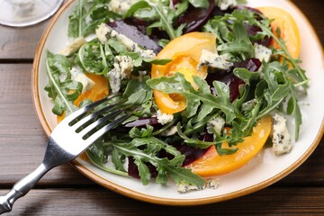 Tasty salad with arugula, blue cheese and vegetables on wooden table, closeup