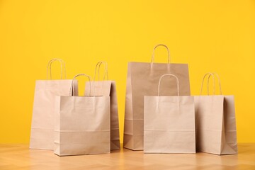 Many kraft paper bags on wooden table against orange background