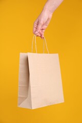Woman with kraft paper bag on orange background, closeup