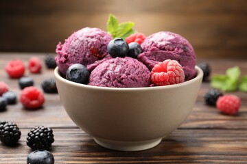 Delicious sorbet with fresh berries and mint in bowl on wooden table against brown background, closeup