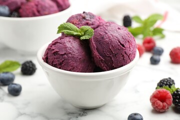 Delicious sorbet in bowl, fresh berries and mint on white marble table, closeup
