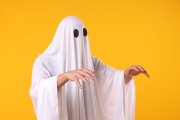 Creepy ghost. Man covered with white sheet on orange background