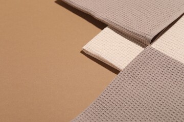 Folded waffle towels on light brown background, closeup. Space for text