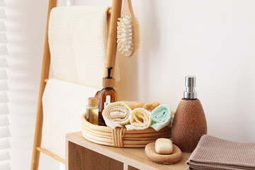 Clean waffle towels and spa products on shelving unit near white wall in bathroom
