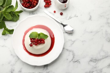 Delicious panna cotta with red currants, sauce and mint on white marble table, flat lay. Space for text