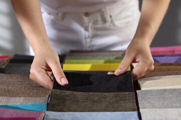 Woman choosing fabric among different samples indoors, closeup