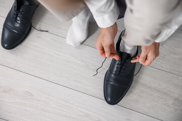 Getting ready. Young man putting on stylish shoes at home, closeup