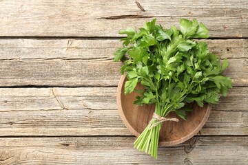 Bunch of fresh parsley on wooden table, top view. Space for text