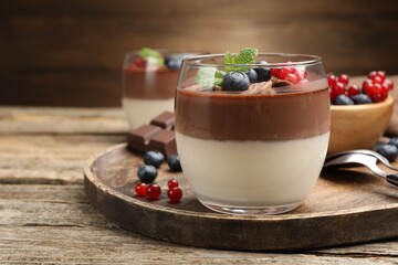 Delicious panna cotta with chocolate, berries and mint on wooden table, closeup