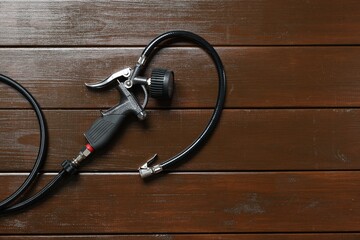 One tire inflation gun with gauge on wooden background, top view