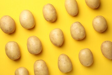 Fresh raw potatoes on yellow background, top view