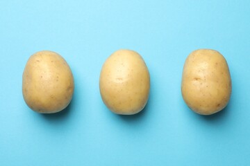 Fototapeta premium Fresh raw potatoes on light blue background, top view