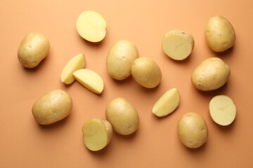 Fresh raw potatoes on light brown background, flat lay
