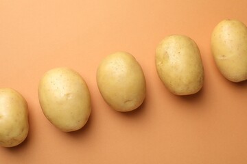 Fresh raw potatoes on light brown background, top view