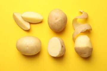 Fresh raw potatoes on yellow background, flat lay