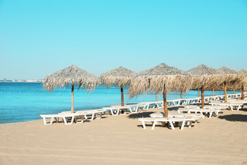 Straw umbrellas and sunbeds on sandy beach