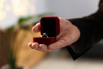 Making proposal. Man with engagement ring indoors, closeup. Bokeh effect