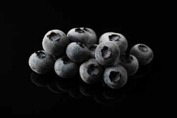 Many frozen blueberries on black table, closeup