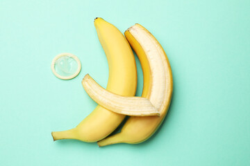 Sex education. Bananas and condom on turquoise background, flat lay