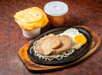 Pork Chop with Noodles and Fried Egg on a Hot Plate side view of hong kong food