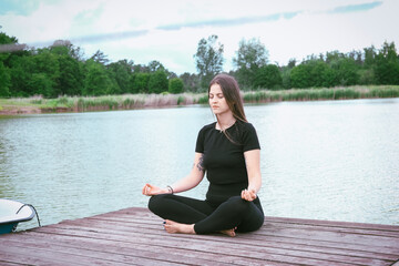 Young woman meditating at morning by the lake
