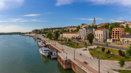 Fototapeta premium Panoramic view of Sava River from Brankov Bridge: boats, promenade, bike lane, historic buildings and St. Michael's Cathedral under summer sky. Belgrade, Serbia.