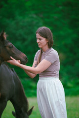 A young woman and her icelandic horse working and cuddle together. Woman lovingly pets a horse in a...