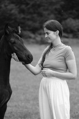 A young woman and her icelandic horse working and cuddle together. Woman lovingly pets a horse in a sunlit field at dusk